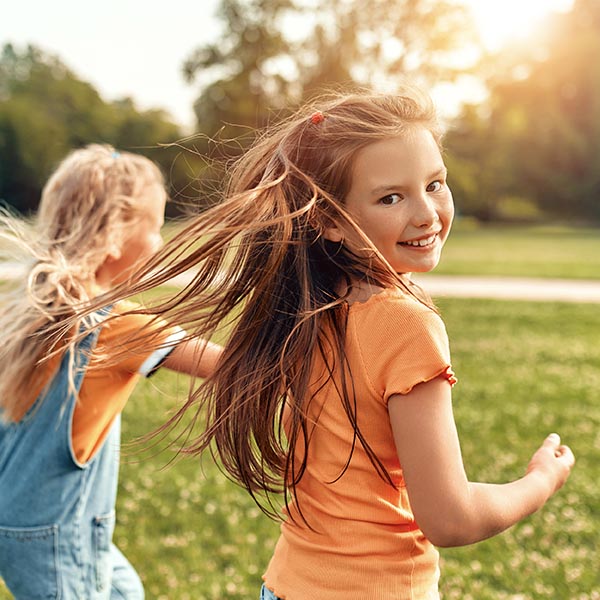 Two little girls running outside in park