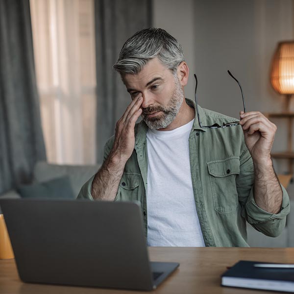 Middle age man working at home office rubbing eye